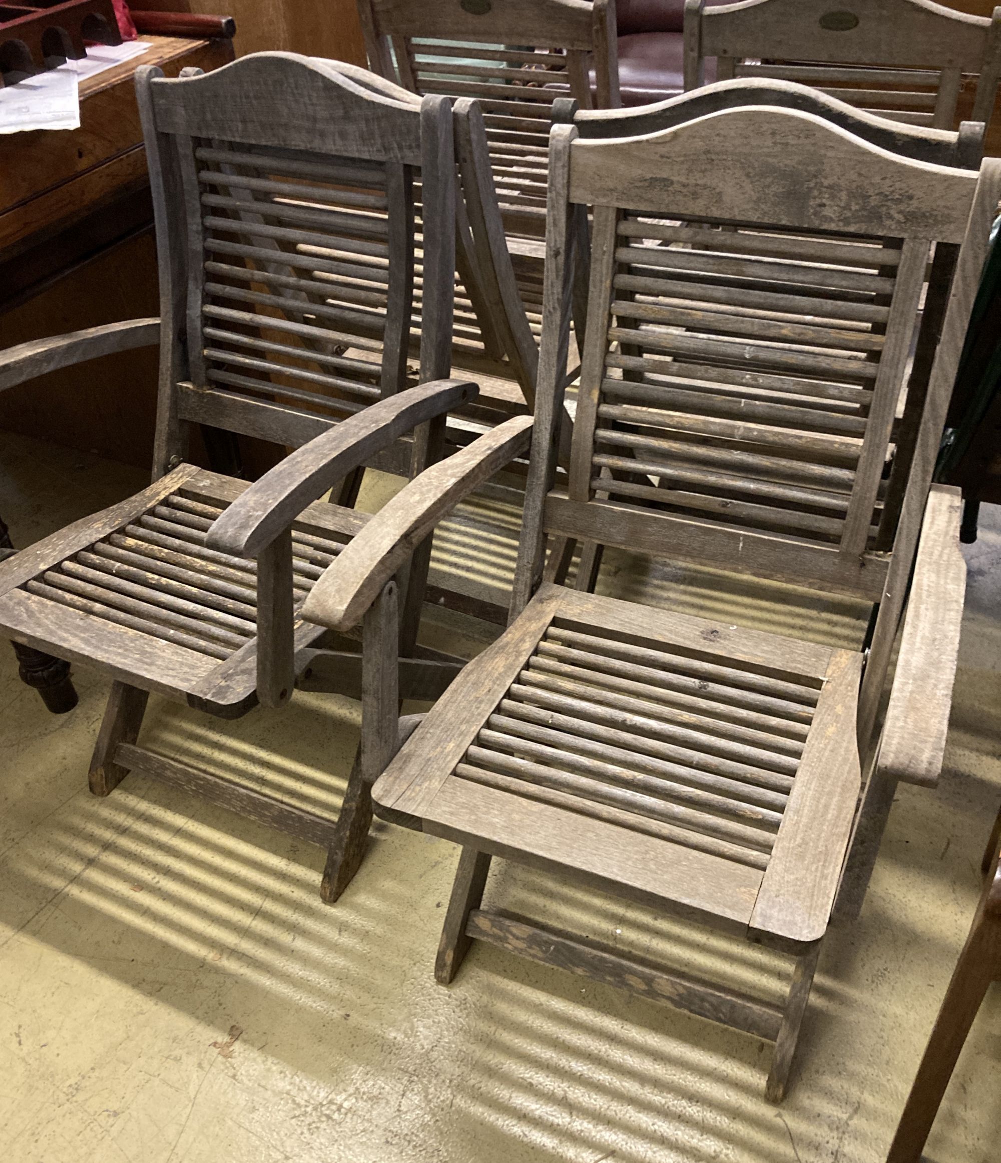 A set of six weathered teak folding garden chairs, two with arms